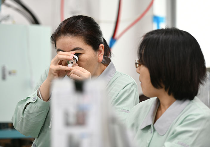 顕微鏡で製品を確認する社員